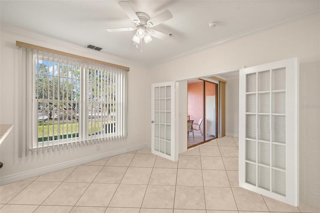 empty room featuring ceiling fan, light tile patterned flooring, crown molding, and french doors