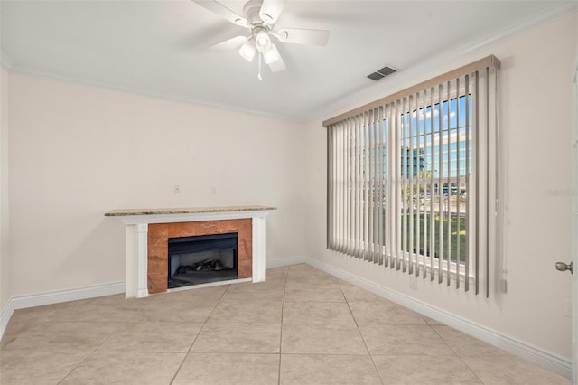 unfurnished living room featuring ceiling fan, crown molding, and a tiled fireplace