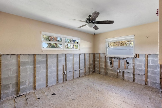 basement featuring plenty of natural light and ceiling fan