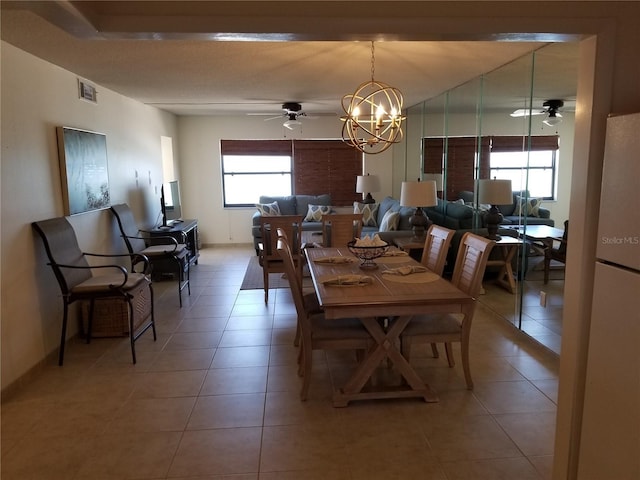 dining area featuring ceiling fan with notable chandelier and light tile patterned flooring