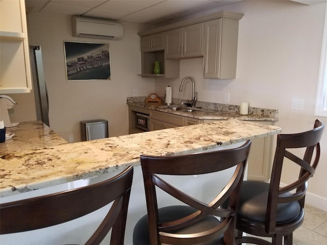 kitchen featuring sink, a kitchen breakfast bar, an AC wall unit, kitchen peninsula, and a paneled ceiling