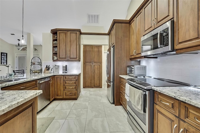 kitchen featuring pendant lighting, light stone counters, sink, and stainless steel appliances