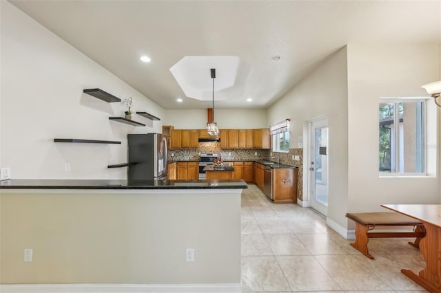 kitchen with kitchen peninsula, decorative backsplash, appliances with stainless steel finishes, sink, and pendant lighting