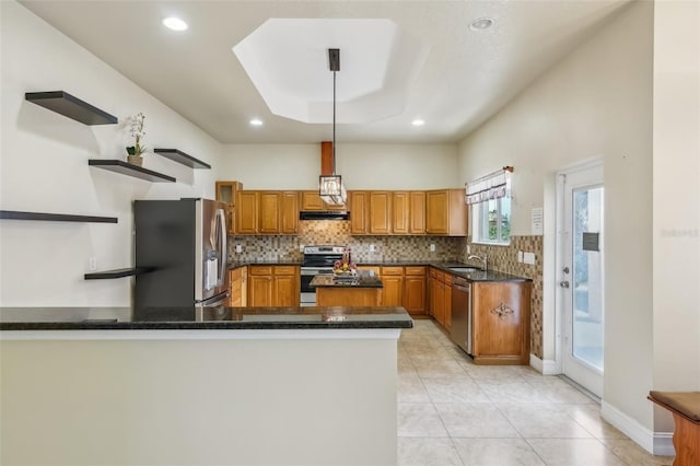 kitchen featuring sink, kitchen peninsula, pendant lighting, a tray ceiling, and appliances with stainless steel finishes