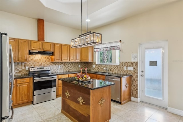 kitchen with dark stone counters, sink, appliances with stainless steel finishes, decorative light fixtures, and a kitchen island