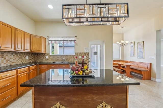 kitchen with decorative backsplash, pendant lighting, a center island, and dark stone countertops