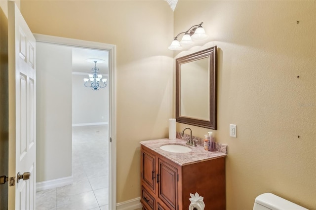 bathroom with toilet, vanity, ornamental molding, and an inviting chandelier