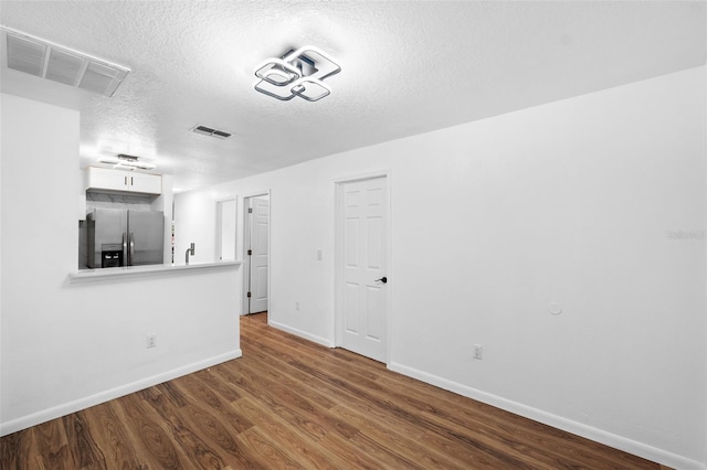 unfurnished living room with a textured ceiling and dark wood-type flooring