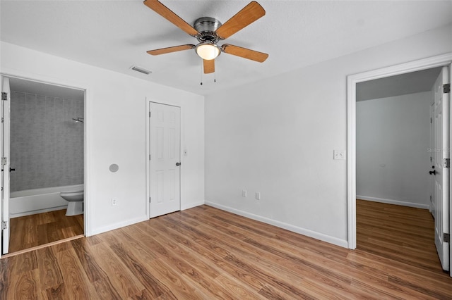 unfurnished bedroom with connected bathroom, ceiling fan, a closet, and light wood-type flooring