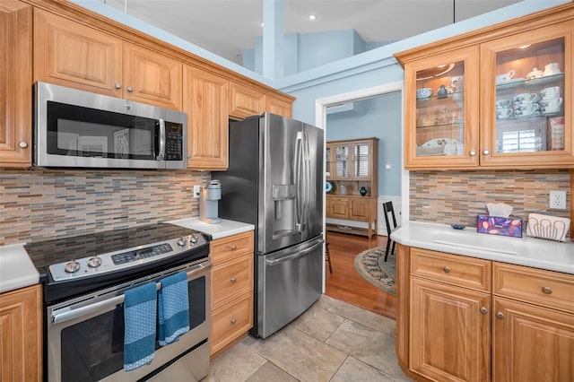 kitchen featuring light tile patterned floors, stainless steel appliances, tasteful backsplash, and lofted ceiling