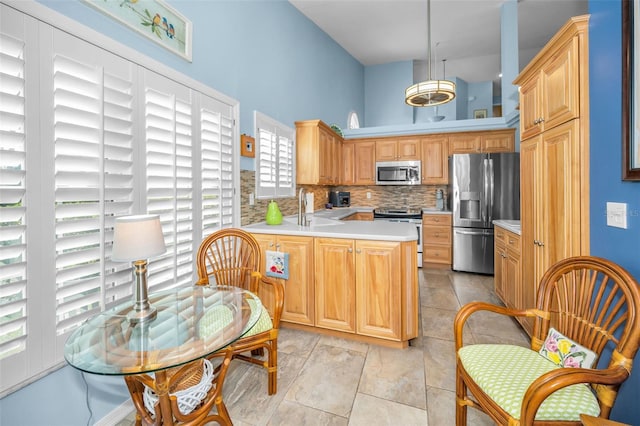 kitchen with sink, stainless steel appliances, tasteful backsplash, kitchen peninsula, and pendant lighting