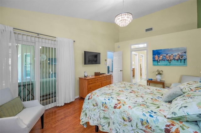 bedroom featuring hardwood / wood-style floors, access to outside, and an inviting chandelier