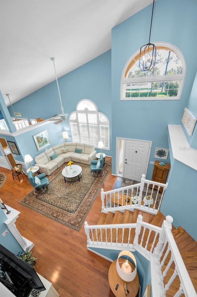 living room featuring ceiling fan with notable chandelier, hardwood / wood-style flooring, and high vaulted ceiling