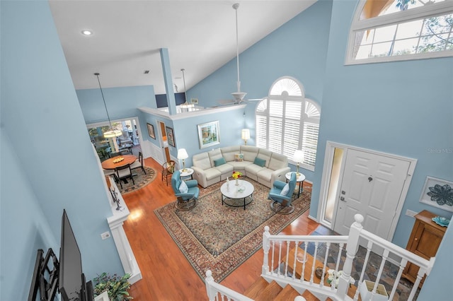 living room with hardwood / wood-style flooring, ceiling fan, and high vaulted ceiling