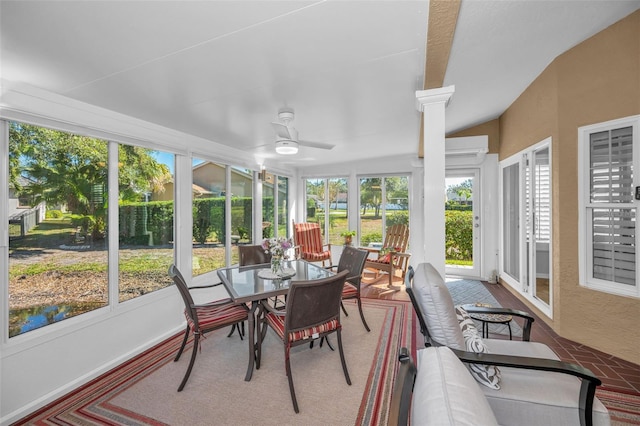 sunroom with ceiling fan, plenty of natural light, a wall unit AC, and ornate columns