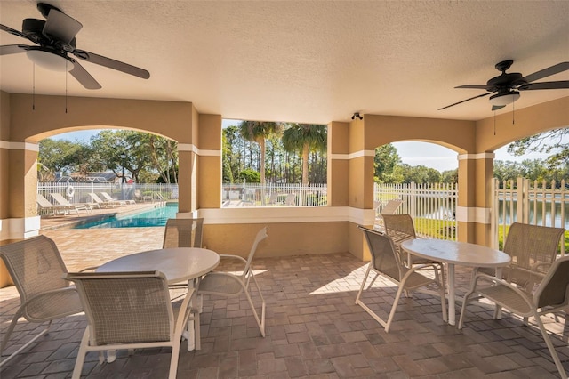 view of patio / terrace with a fenced in pool, ceiling fan, and a water view