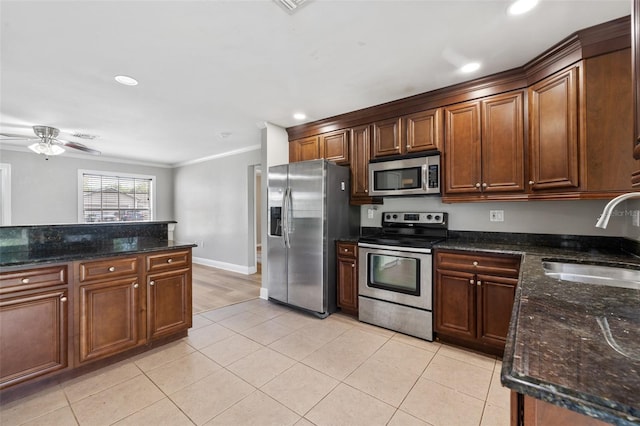 kitchen with ceiling fan, sink, dark stone countertops, appliances with stainless steel finishes, and ornamental molding