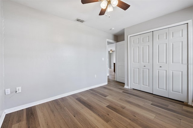 unfurnished bedroom with hardwood / wood-style floors, a closet, and ceiling fan