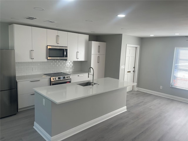 kitchen featuring stainless steel appliances, white cabinetry, a kitchen island with sink, and sink