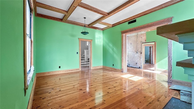 empty room with beamed ceiling, light hardwood / wood-style floors, and coffered ceiling