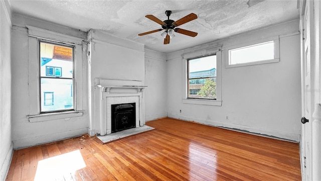 unfurnished living room with hardwood / wood-style floors, a textured ceiling, plenty of natural light, and ceiling fan