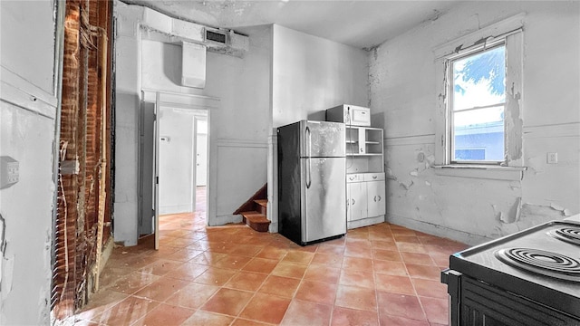 kitchen featuring white cabinets, stove, and stainless steel refrigerator