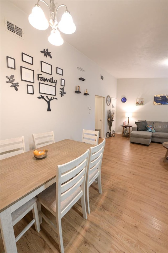 dining room featuring a chandelier, light wood-type flooring, and visible vents