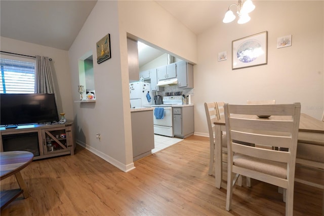 dining area featuring vaulted ceiling, a chandelier, light wood-style flooring, and baseboards