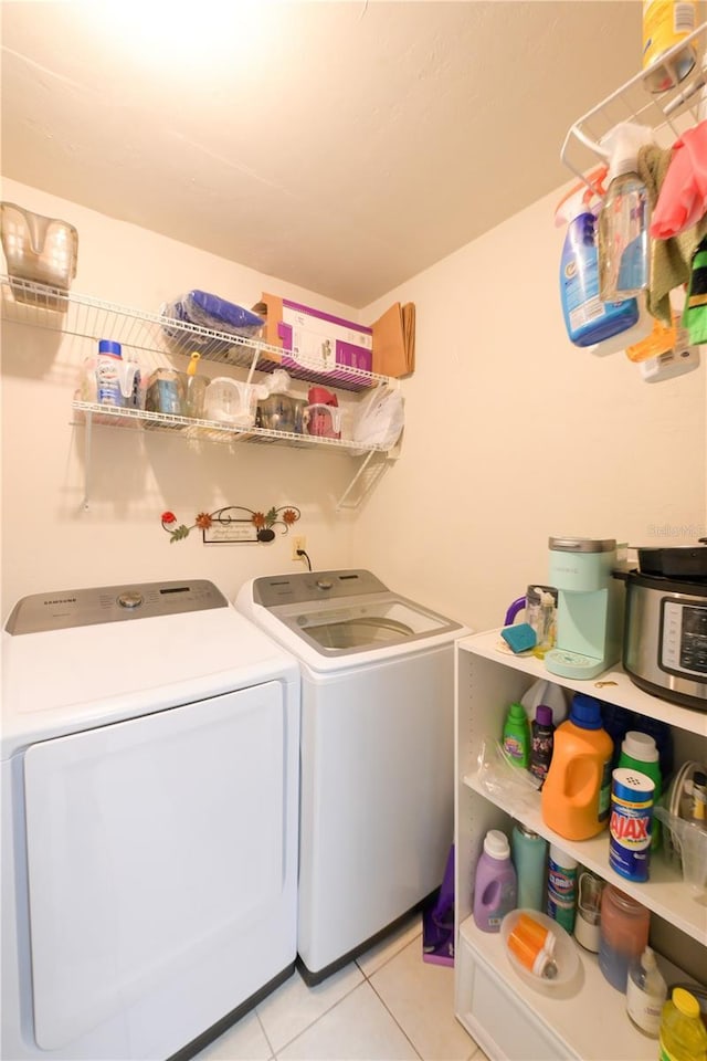 clothes washing area with laundry area, separate washer and dryer, and light tile patterned flooring