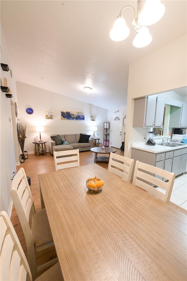 dining area featuring baseboards, light wood finished floors, and an inviting chandelier