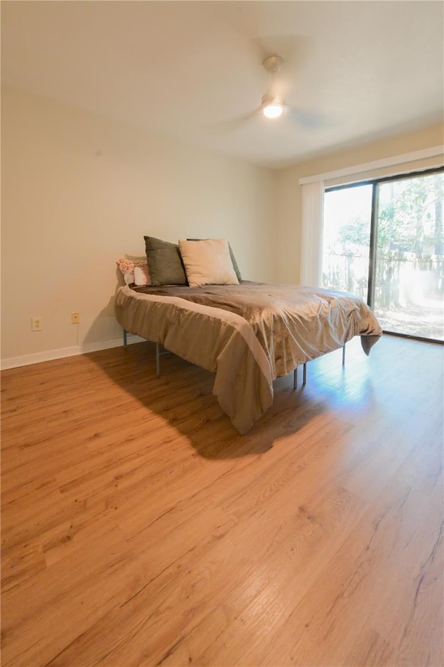 bedroom featuring baseboards, wood finished floors, and access to exterior