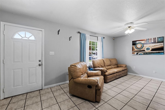 living room featuring ceiling fan, light tile patterned flooring, and a textured ceiling