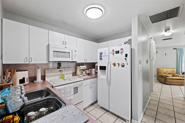 kitchen featuring white appliances, sink, tasteful backsplash, light tile patterned flooring, and white cabinetry