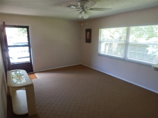 carpeted empty room with ceiling fan and a textured ceiling