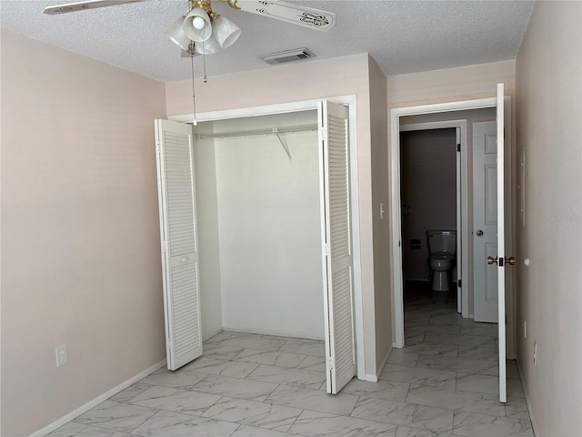 unfurnished bedroom with ceiling fan, a textured ceiling, and a closet