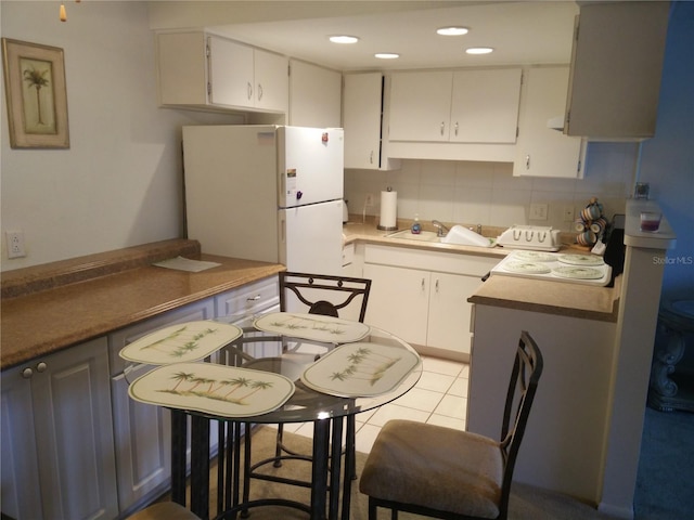 kitchen with white cabinetry, sink, tasteful backsplash, white refrigerator, and light tile patterned flooring