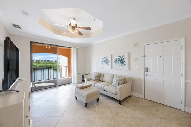 living room with ceiling fan, light tile patterned flooring, crown molding, and a tray ceiling