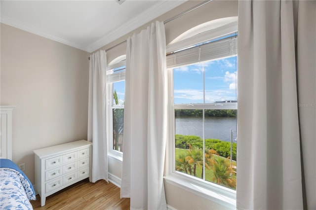 bedroom featuring light hardwood / wood-style floors, a water view, and crown molding