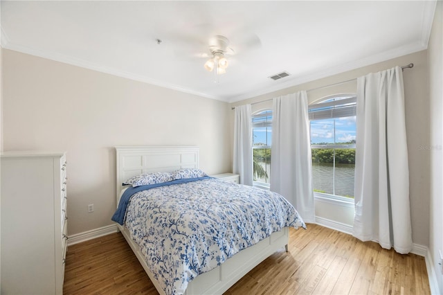 bedroom with hardwood / wood-style floors, ceiling fan, and ornamental molding