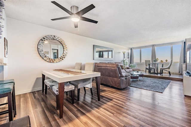 dining space featuring a textured ceiling, ceiling fan, a wall of windows, and dark wood-type flooring