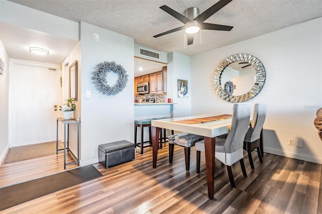 dining room featuring a textured ceiling, hardwood / wood-style flooring, and ceiling fan