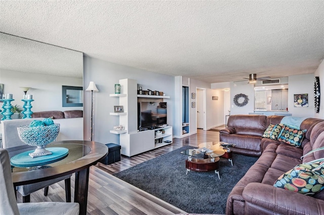 living room with ceiling fan, wood-type flooring, and a textured ceiling