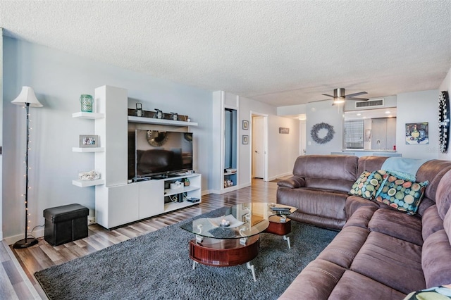 living room featuring a textured ceiling, light wood-type flooring, and ceiling fan