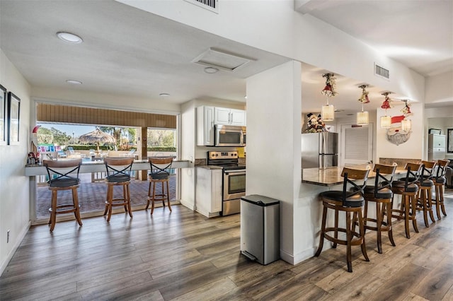 kitchen featuring white cabinets, dark hardwood / wood-style flooring, stainless steel appliances, and hanging light fixtures