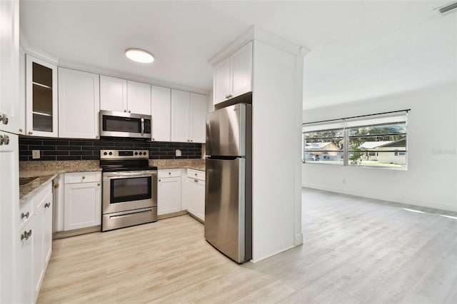 kitchen featuring dark stone counters, white cabinets, light wood-type flooring, and appliances with stainless steel finishes