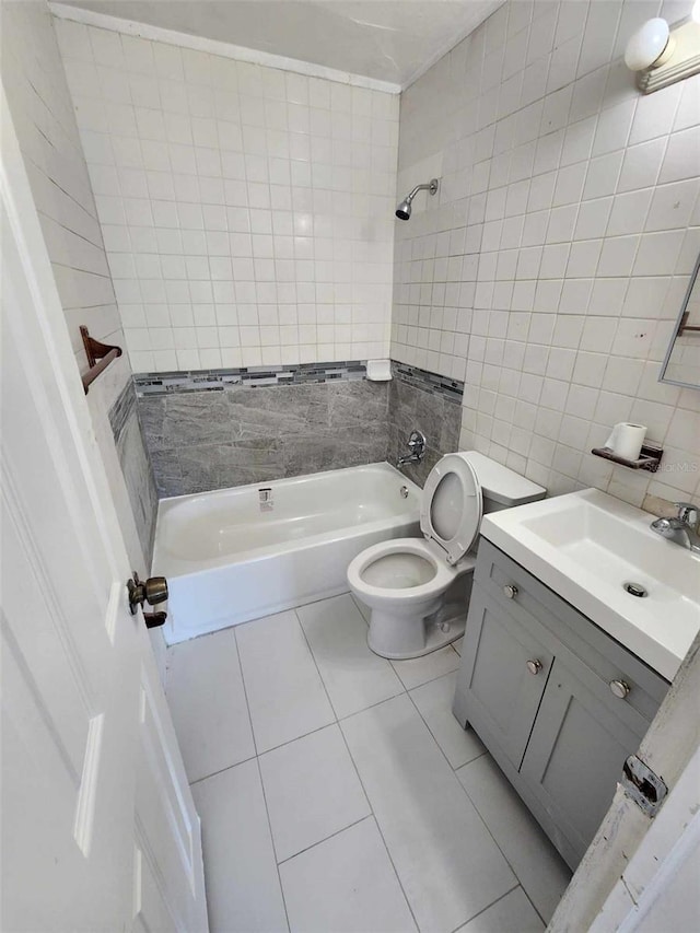 full bathroom with tile walls, tiled shower / bath combo, vanity, toilet, and tile patterned floors