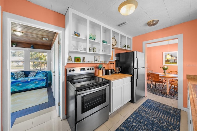 kitchen featuring white cabinets, appliances with stainless steel finishes, butcher block counters, and light tile patterned flooring