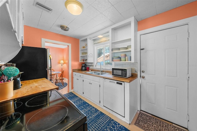 kitchen featuring stove, white dishwasher, refrigerator, built in features, and white cabinetry