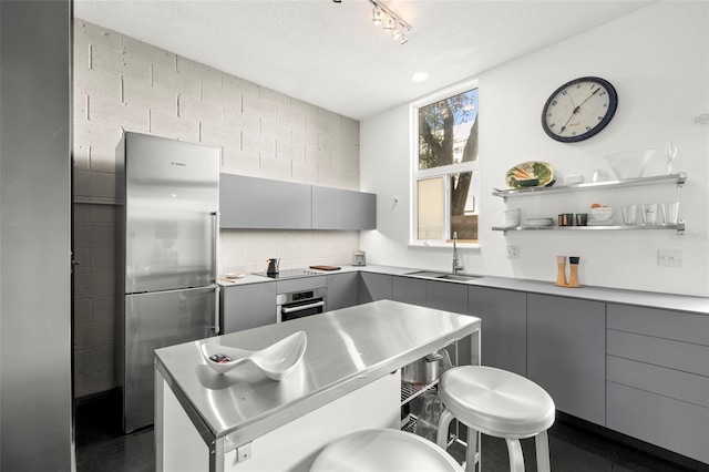 kitchen with a kitchen breakfast bar, sink, gray cabinets, a textured ceiling, and stainless steel appliances