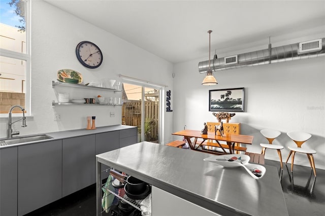 kitchen with gray cabinets, sink, and hanging light fixtures